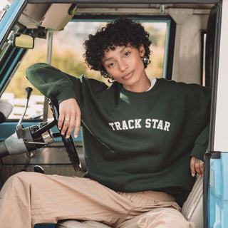 Woman sitting in driver's seat in Track Star crewneck leaning against steering wheel