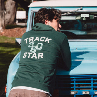 Man leaning against hood of a car showing the back of the Track Star hoodie