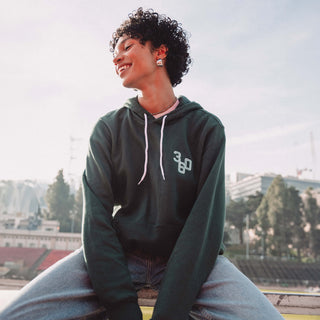 Woman sitting on bench wearing green Track Star hoodie